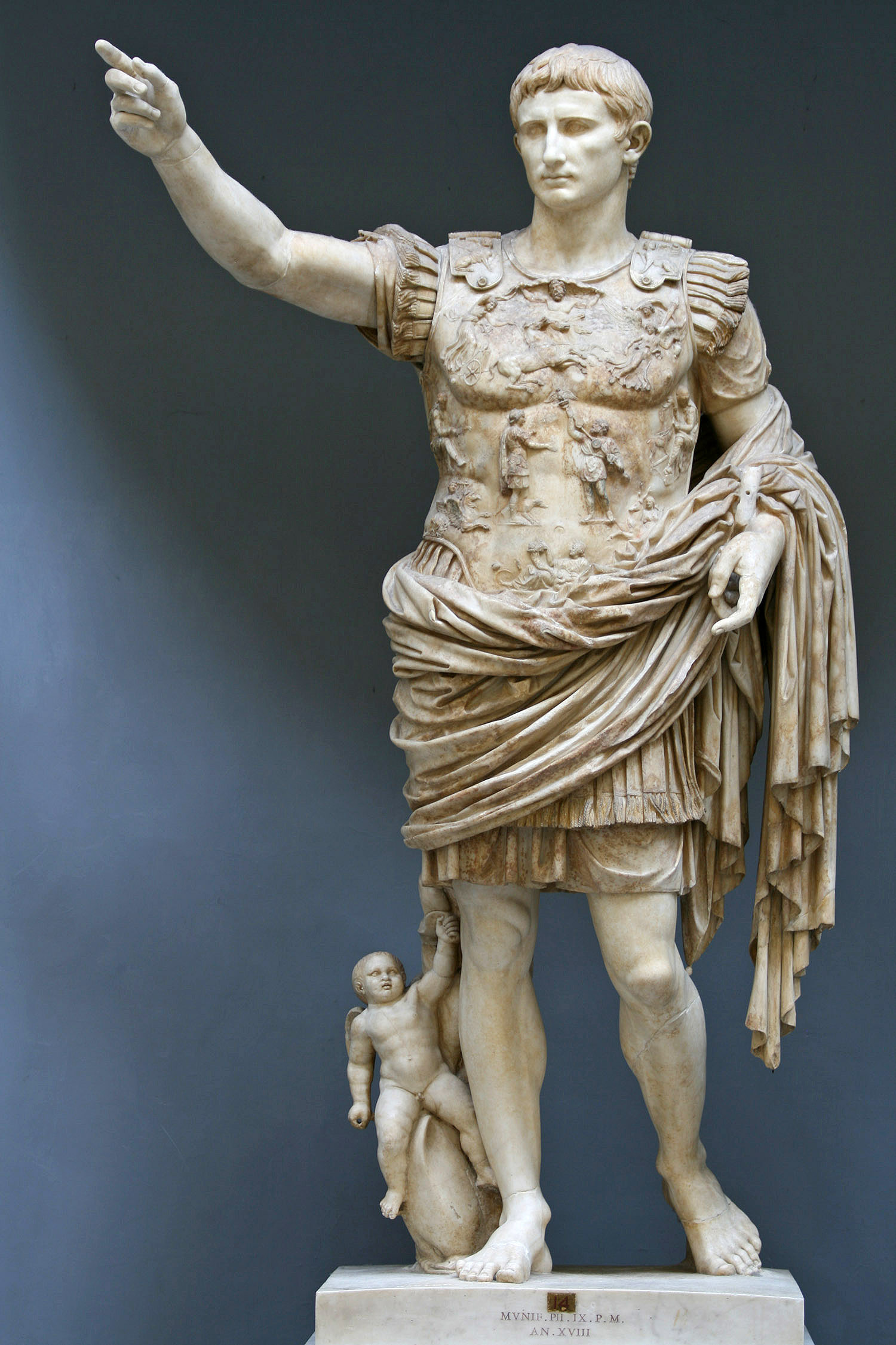 Estátua de mármore de um homem de couraça, com o braço direito erguido.