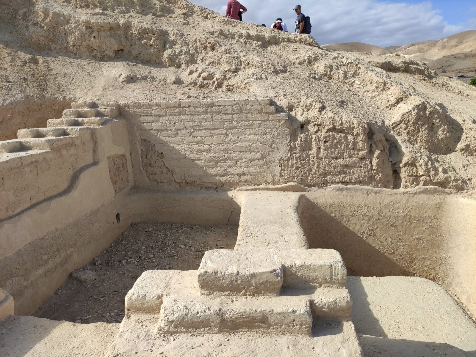 Tanque de pedra rebocada com degraus descendo até o fundo, num sítio escavado no deserto.